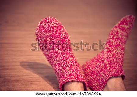 Man Legs in red Wool Socks male knitted clothes winter handmade accessories home comfort concept on wooden background trendy colors