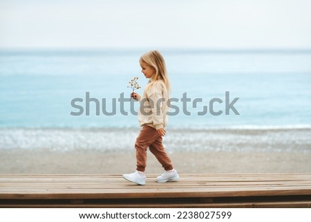 Similar – Image, Stock Photo 4 year old blonde girl with a brightly colored striped sweater sits at a wooden table and draws with a purple pencil on a piece of white paper