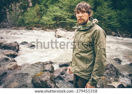 Young Man bearded hiking outdoor with river and forest wild on background Lifestyle Travel survival concept
