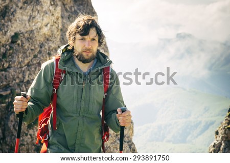 Young Man bearded with backpack and trekking poles relaxing outdoor Travel Lifestyle hiking concept rocky mountains on background Summer vacations