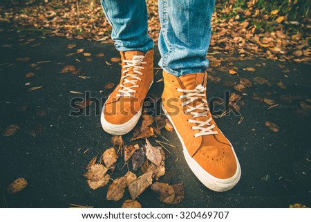 Feet sneakers walking on fall leaves Outdoor with Autumn season nature on background Lifestyle Fashion trendy style