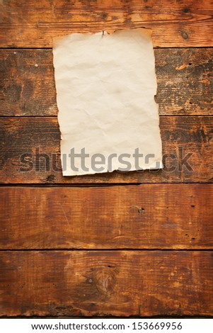 close up of an old worn blank piece of paper with burnt and torn edges, nailed to an old weathered plank door
