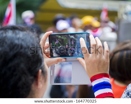 BANGKOK, THAILAND - NOVEMBER 27: Protesters hold an smart phone to share images of anti-government rally against the amnesty bill on November 27, 2013 in Ministry of industry\'s office.