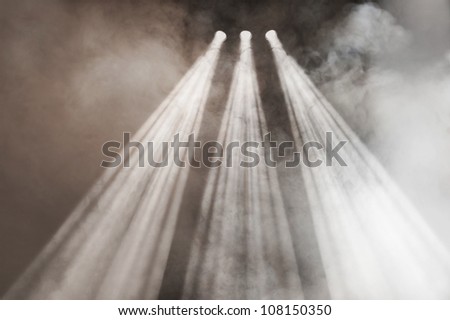 Three spotlights shining down with diverging beams in a smoke-filled atmosphere