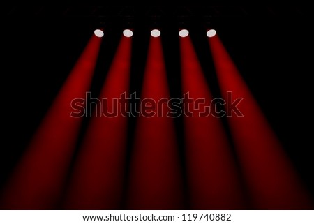 Entertainment background with a line of five red individual symmetrical spotlights shining down through smoky darkness in an empty auditorium, nightclub or theatre