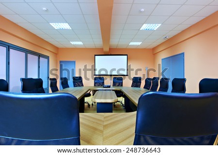 Conference room with empty chairs and a projector screen