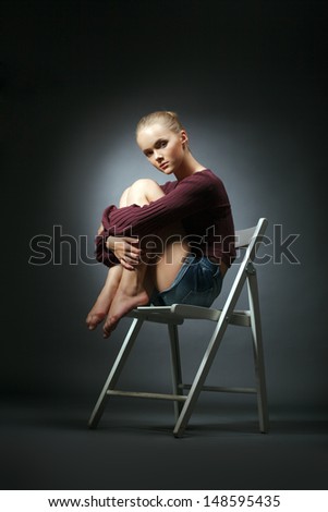 Refined model in stylish clothes sitting on chair