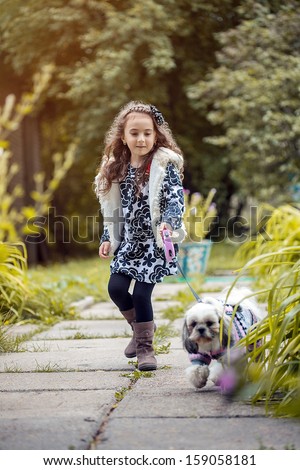 Walk in park - cute girl holding her dog on leash