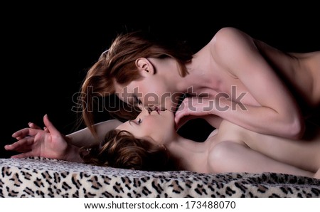 Excited naked girls kissing in studio, close-up