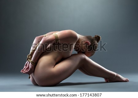 Side view of naked young woman tied with rope
