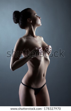 Nude skinny woman covers breasts with her hands