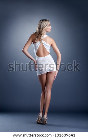 Slender girl posing in short dress, back to camera