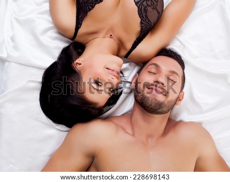 Attractive sexual partners lying on satin sheets