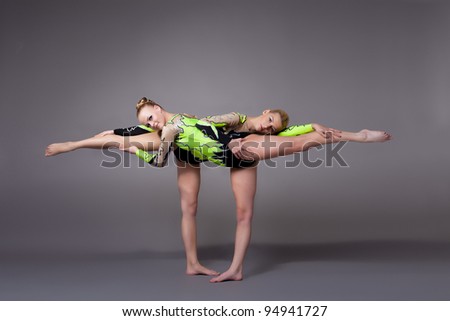 Two young woman as acrobats exercise pair program