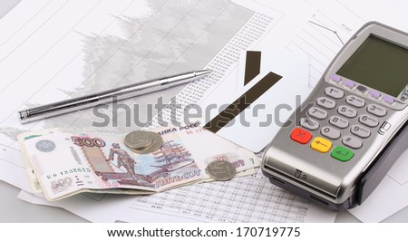 Business still-life of a payment terminal, cards, pen, money, coins