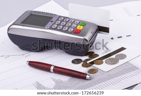 Business still-life of a payment terminal, cards, pen, money, coins