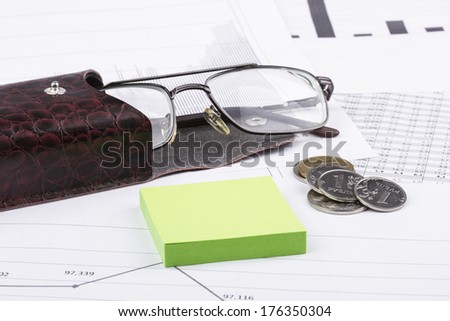 Business still-life of a sticker, money, graphs, eyeglasses, case