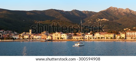Panorama of Marciana Marina harbour with Monte Cappane mountain in backround, rocks and yacht in bay on island Elba, Tuscany, Italy, Europe