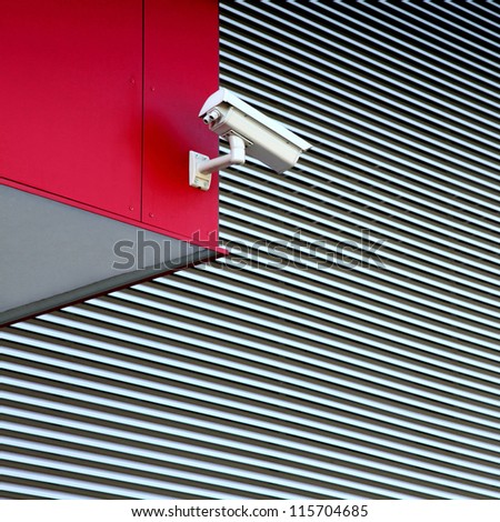 White security camera on red building.