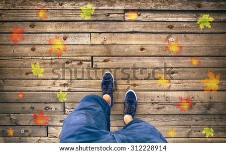 A man walking on aged wooden floor with autumn season leaves, point of view perspective. Autumn season man walk. Conceptual autumn season photo, point of view perspective used.