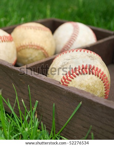 old baseballs in a wooden box on the field, focus on foreground ball