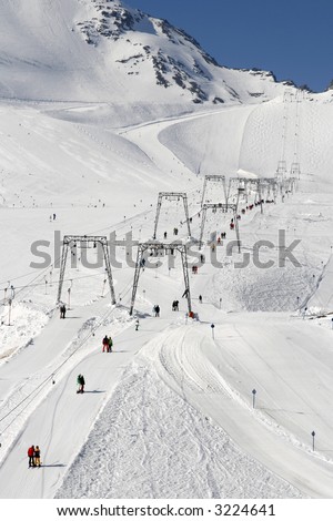 Ski drag lift in winter landscape and people skiing