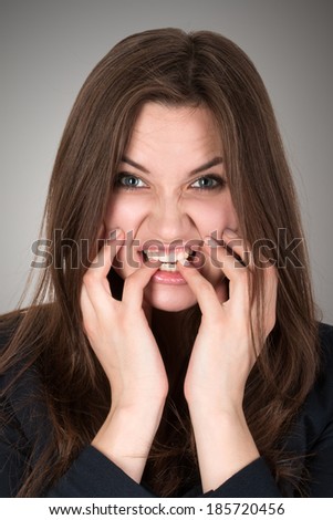 Frightened and stressed young business woman biting her fingers