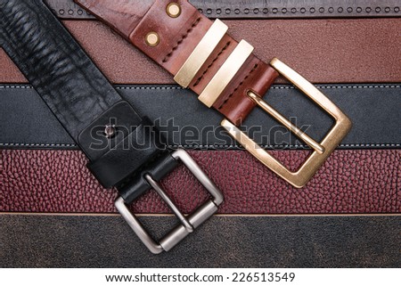 Close-up of two men belts over leather strips background