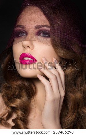 Portrait of young beautiful aristocratic woman with bright pink lips wearing purple veil and touching her face
