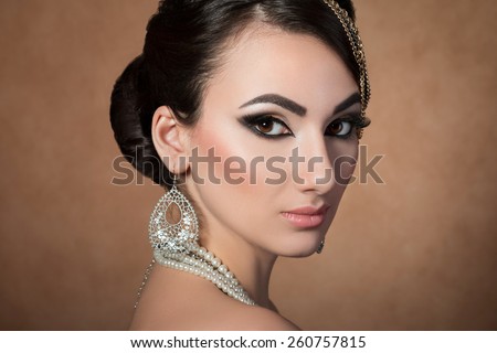 Portrait of young beautiful asian woman with evening make-up over beige background