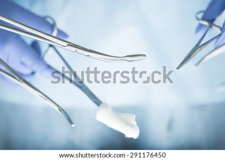 Close-up of doctor\'s hands holding surgical clamps. Medical background