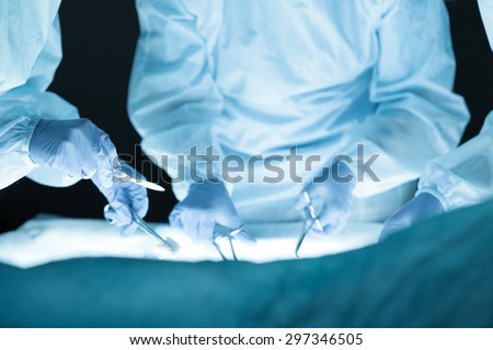 Medical team performing operation. Group of surgeon at work in operating theatre. Hands close-up view