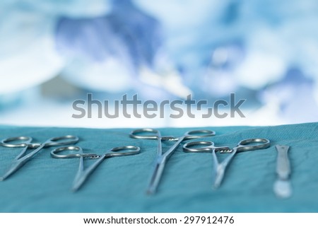 Close-up of medical instruments with surgeons performing operation at background