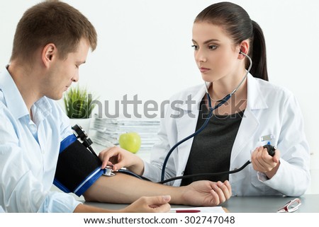 Young female medicine doctor measuring blood pressure to patient. Medical and healthcare concept