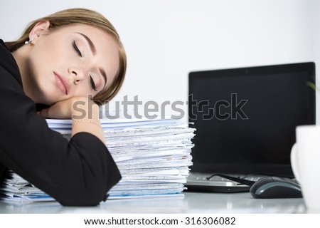 Tired business woman slleeping on heap of papers at her working place. Overwork, working overtime and stress at work concept.