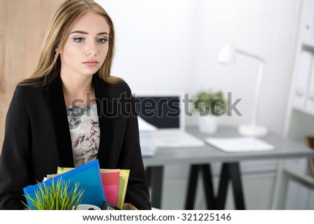 Young dismissed female worker in office holding carton box with her belongings. Getting fired concept. Copy space.