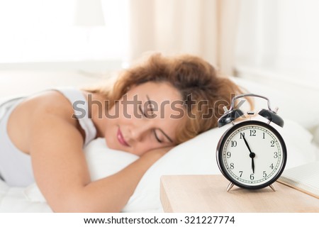 Beautiful happy woman sleeping in her bedroom in the morning. Well being and healthy sleeping concept.