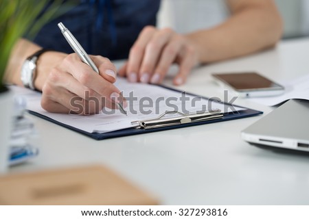 Close-up of female hands. Woman writing something sitting at her office. Signing documents