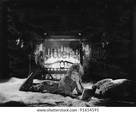 Woman reading book by the fire