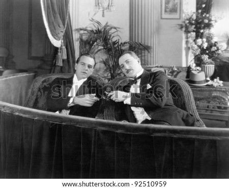 Two men in formal attire sitting together in a theater box