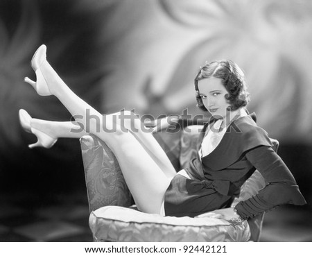 Young woman sitting on a chair with her legs up in the air