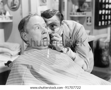 Barber looking at a man\'s face through a magnifying glass