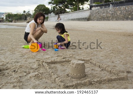 Mother and daughter building sand castle on the beach