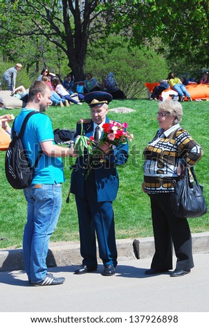 MOSCOW, RUSSIA - MAY 09: A young man gives flowers to a war veteran. Victory Day celebration in the Gorky park on May 09, 2013 in Moscow.
