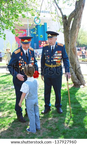MOSCOW, RUSSIA - MAY 09: A boy gives flowers to war veterans flowers. Victory Day celebration in the Gorky park on May 09, 2013 in Moscow.