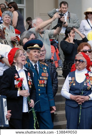 MOSCOW, RUSSIA - MAY 09: War veterans sing war songs on the Theater Square, by the Bolshoi Theater, traditional place for veterans\' meeting. Taken on May 09, 2013 in Moscow.
