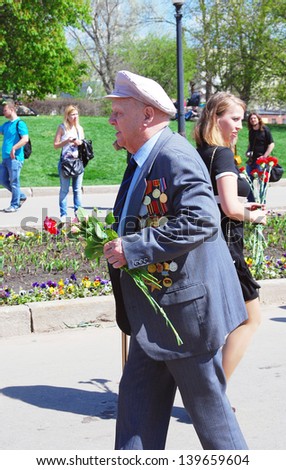MOSCOW, RUSSIA - MAY 09: A war veteran walks with flowers. Victory Day celebration in the Gorky park on May 09, 2013 in Moscow.