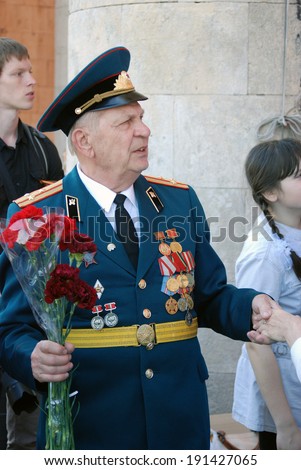 MOSCOW, RUSSIA - MAY 09, 2013: A war veteran holds flowers. Victory Day celebration in the Gorky park in Moscow.