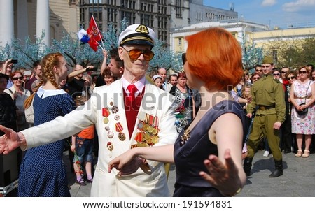 MOSCOW, RUSSIA - MAY 09: Senior war veteral dances with a redhead woman on the Theater Square, by the Bolshoi Theater. Victory Day celebration on May 09, 2013 in Moscow.