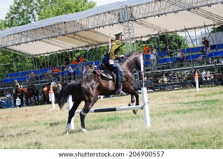 MOSCOW - JUNE 08, 2014: A horse jumps over the border. Horse riders competition. A rider is dressed in vintage military uniform. Times and Ages International Historical Festival, Kolomenskoye, Moscow.